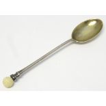 A silver spoon with gilded bowl. Surmounted by a golf ball.