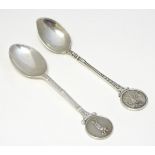 Two silver spoons, the handles decorated with images of golfers.