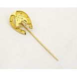 An 18ct gold stick pin surmounted by horseshoe and horse head detail.