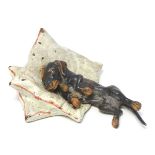 A novelty cold painted bronze figure group depicting a dachshund dog asleep on cushions.
