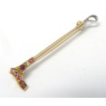 A gold brooch formed as riding crop / whip set with red and white stones.