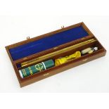 A walnut cased 12 bore shotgun cleaning kit, comprising two-piece wooden rod, woolen mop,