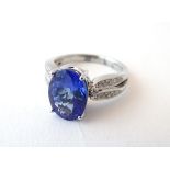 A platinum ring set with central blue iolite flanked by diamonds. Ring size approx.