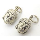 A pair of novelty white metal charms formed as buddha heads. ( Unmarked, tests as silver).