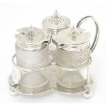 A silver trefoil formed cruet stand with three glass and silver cruet bottles.