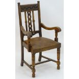 An early 20thC oak open armchair with a Celtic style carved top rail and back ress,