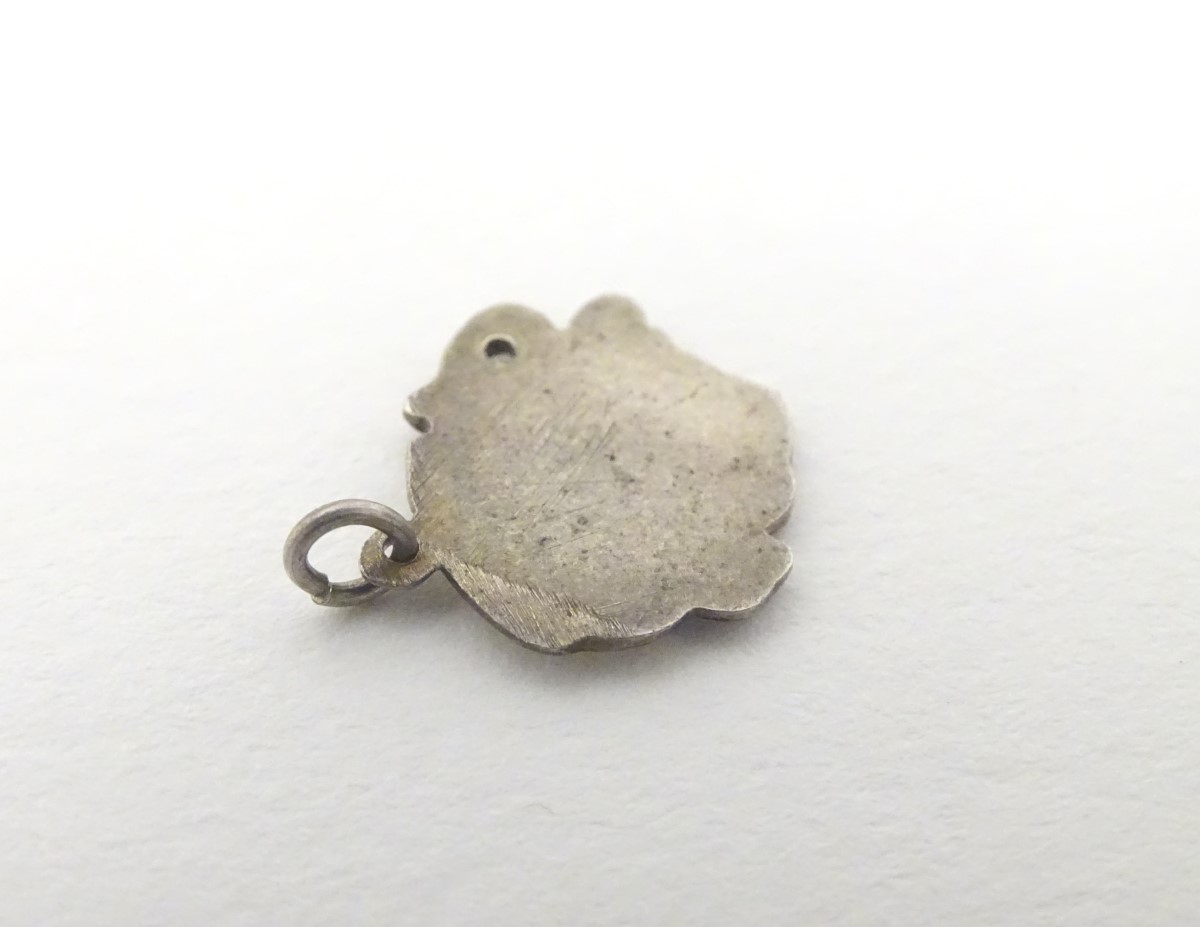 A mid 20thC novelty white metal pendant charm formed as a humorous face wearing a chamber pot as a - Image 4 of 5