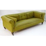A large Victorian Chesterfield style sofa raised on turned legs terminating in ceramic castors.