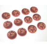 12 French retro buttons with two holes, decorated with colourful chevrons in relief on a red ground.