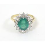 An 18ct gold ring set with central emerald bordered by diamonds. The setting approx ¾” x ½” overall.
