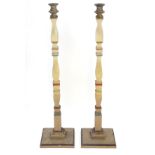 A pair of 20thC tall squared based candlesticks of carved wooden form with painted decoration and