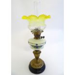 An early 20thC oil lamp, the frosted yellow glass shade with etched clear floral motifs,
