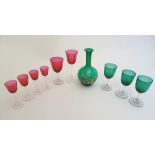 Assorted Cranberry and green glassware including pedestal drinking glasses and a carafe.