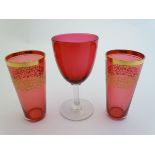 Two cranberry glasses beakers / pony measures with gilt decoration together with a cranberry glass