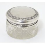 A cut glass dressing table pot with silver lid, having banded Greek key decoration.