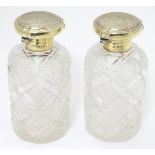 A pair of cut glass scent flasks / bottles with silver gilt tops with engine turned decoration.