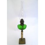 An early 20thC oil lamp, the green glass reservoir supported by an onyx and brass column and base,