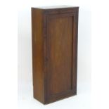 An early 20thC mahogany cupboard with a single panelled door opening to reveal fitted shelves