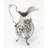 A Continental silver jug with floral and c-scroll decoration and central pictorial vignette.
