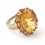 A 9ct gold dress ring set with central facet cut citrine bordered by further citrines.