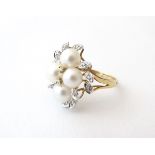 A 9ct gold dress ring set with four pearls and diamonds in a foliate setting. Ring size approx.