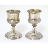 A pair of silver pedestal egg cups with gilded interiors.