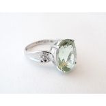A 9ct white gold ring set with a pale green stone, possibly a paraiba, flanked by diamonds.