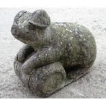 A 20thC reconstituted stone model of a pig resting on a barrel,