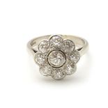 An 18ct white gold ring set with central old cut diamond bordered by 8 further diamonds in a daisy