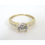 A 14 ct gold ring set with a large central cubic zirconia flanked by 3 baguette cut cubic zirconia