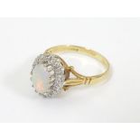 An 18ct gold ring set with central opal bordered by diamonds. Ring size approx. P.