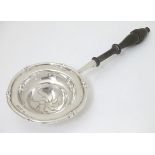 A silver tea strainer with turned wooden handle.