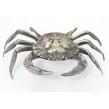 A white metal model of a crab, the body forming a small box with shell section hinging open.