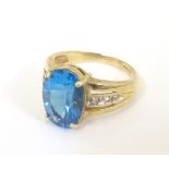 A 9ct gold ring set with central topaz flanked by white stones to shoulders.