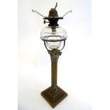 A late Victorian oil lamp, the clear glass reservoir supported by a brass corinthian column.