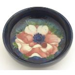 A 20thC Moorcroft circular dish decorated with an anemone flower on a blue ground. Marked under.