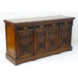 A Victorian walnut three drawer sideboard with pilaster decoration flanking and separating the four