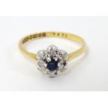 An 18ct gold ring set with central sapphire bordered by diamonds.