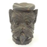 A late 20thC tobacco jar in the black forest style formed as the head of a dog wearing a hat and