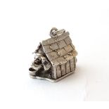 A novelty white metal charm formed as a dog in a dog kennel, hinging open .