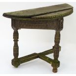 An antique credence table with a demi lune top and carved frame.