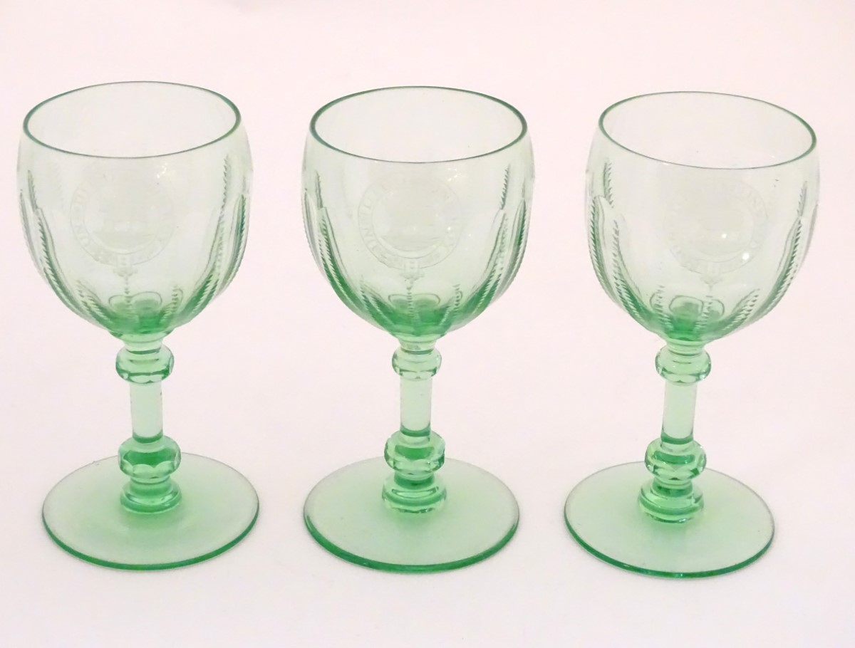Three green glass pedestal wine glasses with engraved armorial depicting a bull and titled with