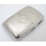 A silver cigar case with hammered decoration hallmarked Birmingham 1906 maker Thomas Bishton.