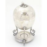 A William Hutton & Sons Cross Arrows silver plate egg coddler of oval form raised on three scrolled