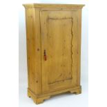 A 20thC pine cupboard with a moulded cornice above carved panelled door and shaped bracket feet.