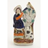 A Victorian Staffordshire pottery flatback model of a woman wearing a sash feeding a bird next to a
