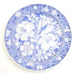 A 20thC blue and white hand painted plate decorated with flowers, lilies, foliage and butterflies.