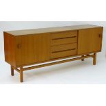 Vintage/Retro: A long teak sideboard having two sliding doors opening to reveal shelves within