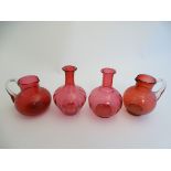 4 assorted items of cranberry glass comprising jugs and carafes.