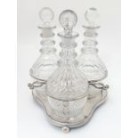 A 19thC silver plate 3-bottle decanter stand / tantalus containing a set of three cut glass